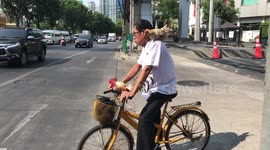 Cyclist takes chicken for a ride during morning rush hour in Thailand