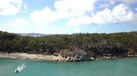 Slow rising Aerial View towards WhiteHaven Beach with a departing dinghy Boat