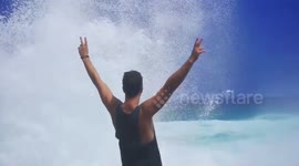 Daring tourist sprayed by giant wave whilst standing on Devil's Tears cliffs in Indonesia