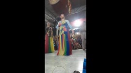 The woman uses her head to lift a large drum and another woman