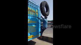 Man perfectly balances a huge tyre on his head as he climbs on the roof of a bus