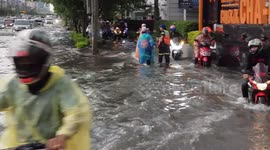Motorcyclists ride through flooded road after heavy rain in Bangkok