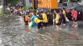 School children wade through water after flash floods in Bangkok