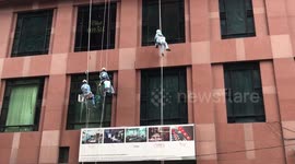 Men hang in a dangerous job cleaning windows