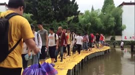 Teachers use tables to build bridge so students can walk across flooded courtyard in China