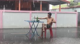 Wind and rain won't stop this Thai man from popping a beer and noodles