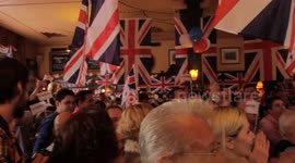 Pearly Kings & Queens sing in packed London pub while crowd waves British flags and join in. The song is