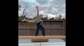 Daughter supports her dad as he attempts to cartwheel on a balance beam in Australia