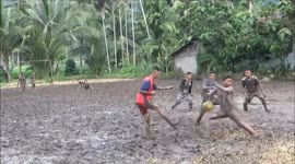 Indonesian teenagers attempt to play soccer in the thick mud of a rice field
