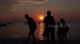 Tourists take photos of a beautiful sunset on a beach in Thailand