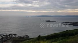 HMS Queen Elizabeth Aircraft carrier . And anti submarine  helicopters scouting the sea around its moorings of plymouth