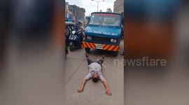 A man lay down in front of towing van on busy road in protest for his towed motorbike in India.
