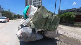 Ridiculously overloaded motorcycles carrying large sacks move quickly on the road