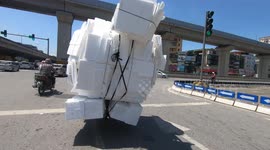 Ridiculously overloaded bike carrying foam boxes staggered on the road