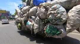 Man driving an overloaded tricycle carrying 19 huge sacks filled with waste and lots of plastic bottles