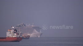 The large cruise ship MSC Seaview arriving into Barcelona port at sunrise with cargo ship in the foreground