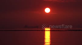A large beam of light on the ocean from a setting sun