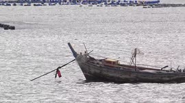 An old fishing boat moored in a silvery ocean.