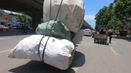 Sacks fly on the road? Man driving an overloaded tricycle carries huge sacks in Vietnam