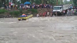 Passengers watch on as bus flips over in raging river in the Philippines