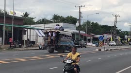 Reckless schoolboys climb onto roof of moving bus on busy road in Thailand