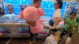 A young man tried to pick up a stuffed animal in stuffed animal game machine and gave it to his girlfriend