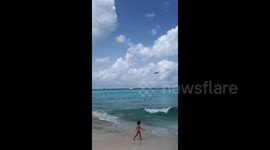 Beachgoers watch as planes fly low over Caribbean beach