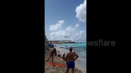 Beachgoers watch as planes fly low over Caribbean beach