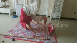 Elderly Chinese man headstands while practising calligraphy with his foot