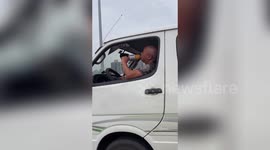 Man sings into microphone while driving along road in China's Chongqing