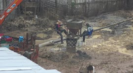 Builders continue working from a crane in the rain in Thailand