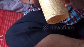 A lady weaves a small basket from bamboo material in Thailand.