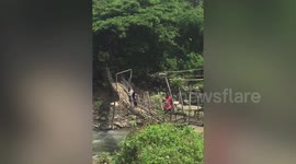 Filipino locals choose between fording a river in their cars or crossing a rickety wooden bridge