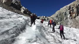 Sherpa crossing an extremely slippery glacier with a heavy bag.