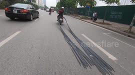 It is so awful! Man drives a motorbike carrying a 6 meter long bundle of steel on a crowded street in Vietnam