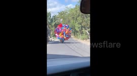 Real-life Up? Balloon man on motorbike struggles not to get blown away by wind