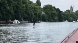 Man on a hover surfboard zooms along the River Thames