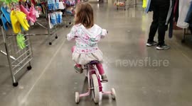 Kid Bikes Through Thrift Shop on Training Wheels