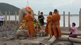 Thai locals flock to sunken Buddhist temple that has emerged from the water after severe drought