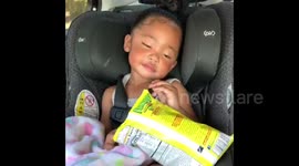 Precious toddler tries her best to stay awake while eating snacks