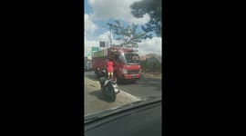 Man rides down busy road on motor scooter while bringing child standing on the seat
