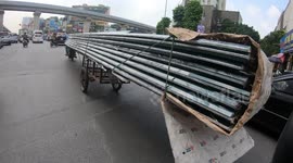 Man driving a motorbike carrying large metal plates and more than 10 meters long in Vietnam