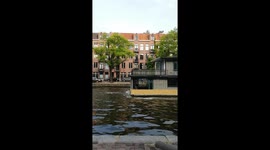 Moving house in Amsterdam: Tugboats pull two-storey houseboat along canal