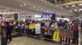 Passengers walk by crowds of protesters at Hong Kong airport