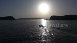 Drone filming a boat at sunrise on the ocean
