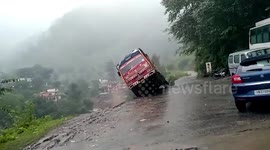 Pedestrians watch on as truck topples off cliff during landslide in northern India