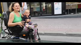 A woman in wheelchair drive her baby in her lap -  Motherly love