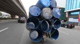 Crazy overloaded motorcycles carrying 10 giant metal barrels on a crowded street in Vietnam