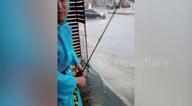 Locals go fishing on flooded road as Tropical Storm Podol hits northern Thailand