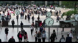 crowds walking in canary wharf, london docklands, with the famous clocks